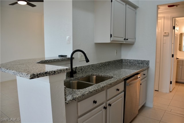 kitchen featuring kitchen peninsula, light stone counters, stainless steel dishwasher, light tile patterned flooring, and sink