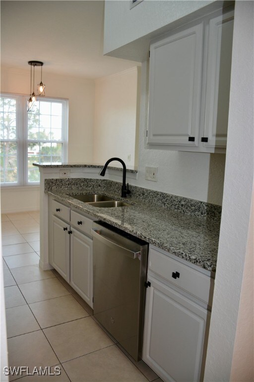 kitchen with dishwasher, sink, light stone countertops, pendant lighting, and white cabinetry