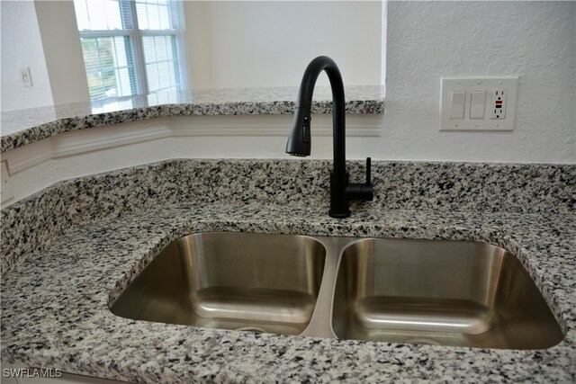 interior details featuring sink and light stone countertops