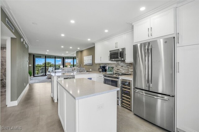 kitchen with kitchen peninsula, appliances with stainless steel finishes, white cabinetry, and sink