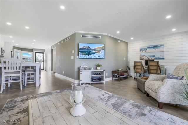 living room featuring concrete flooring, crown molding, and wood walls