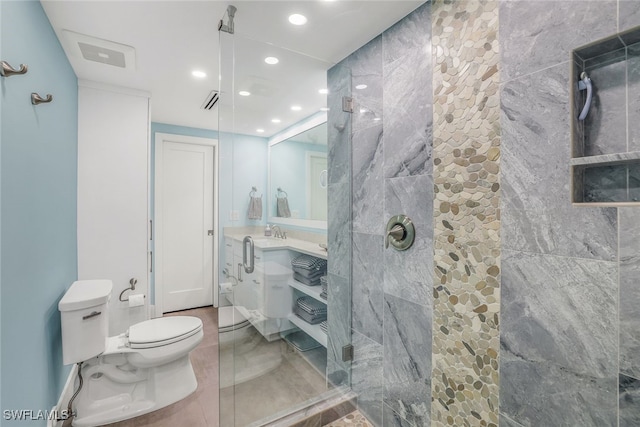 bathroom featuring toilet, a shower with shower door, and sink