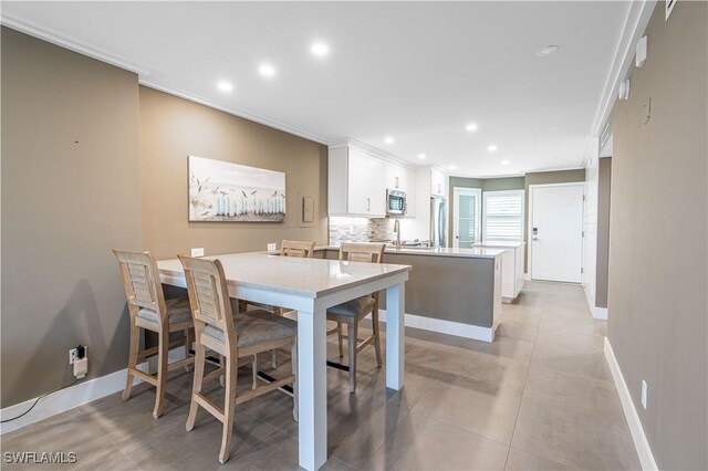 tiled dining space featuring crown molding and sink