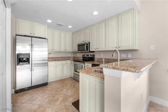 kitchen with light tile patterned flooring, appliances with stainless steel finishes, sink, a kitchen breakfast bar, and kitchen peninsula