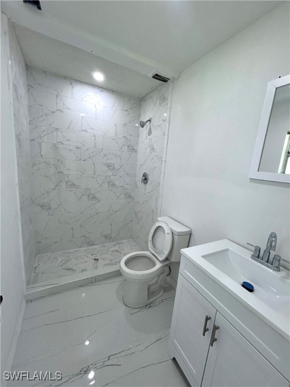 bathroom with vanity, toilet, and a tile shower