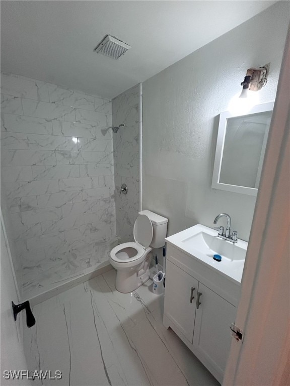 bathroom with vanity, toilet, and tiled shower