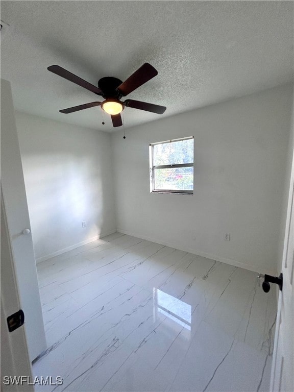 unfurnished room with ceiling fan and a textured ceiling