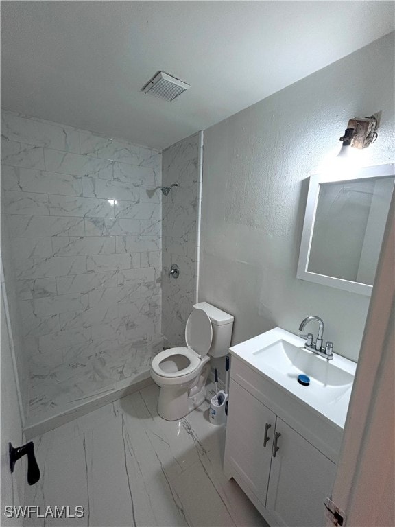 bathroom with vanity, toilet, and tiled shower