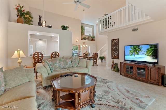 living room with tile patterned floors, ceiling fan with notable chandelier, and a high ceiling