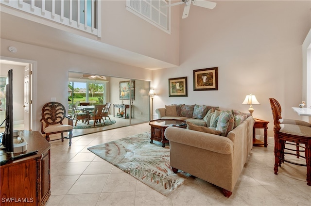 living room featuring ceiling fan, light tile patterned floors, and a high ceiling