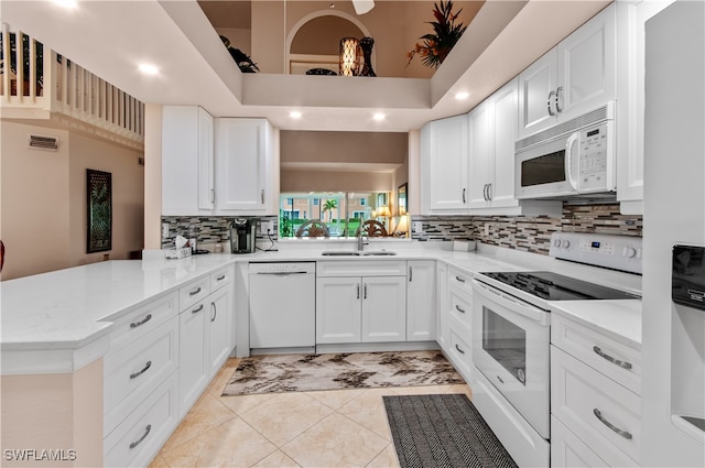 kitchen featuring kitchen peninsula, white appliances, white cabinetry, and sink