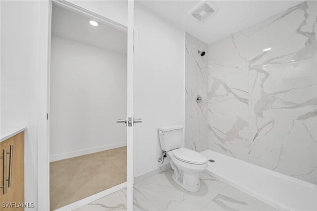 bathroom with tiled shower, vanity, and toilet