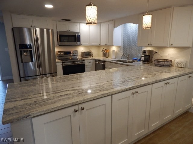 kitchen featuring appliances with stainless steel finishes, white cabinetry, and pendant lighting