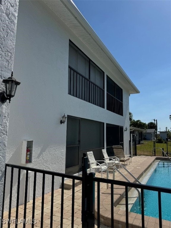 rear view of property with a fenced in pool and a patio area