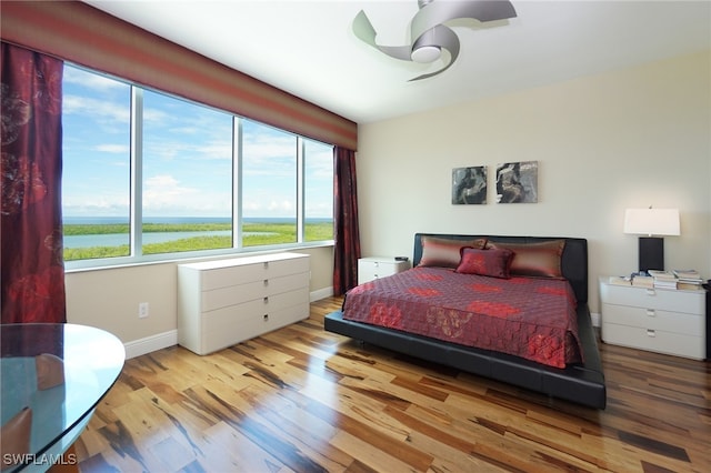 bedroom featuring light hardwood / wood-style flooring and a water view