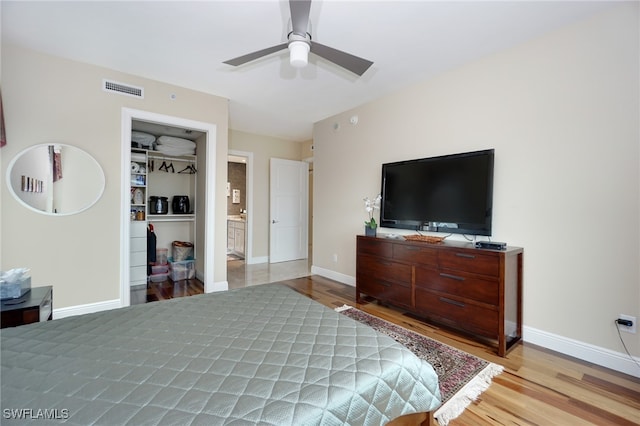 bedroom with ceiling fan, a closet, light wood-type flooring, and a spacious closet