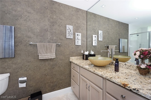 bathroom with toilet, vanity, and a shower with door