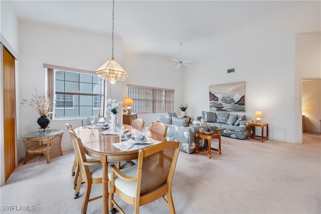 dining area with high vaulted ceiling, light colored carpet, and ceiling fan