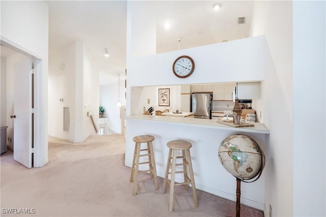 2141 Tama Cir Unit 202, Naples, FL 34112 - kitchen featuring freestanding refrigerator, light colored carpet, a kitchen breakfast bar, a peninsula, and light countertops