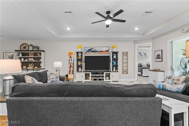 living room featuring a raised ceiling and ceiling fan