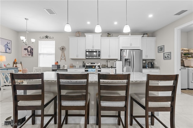 kitchen featuring a center island with sink, stainless steel appliances, a breakfast bar, and washing machine and clothes dryer