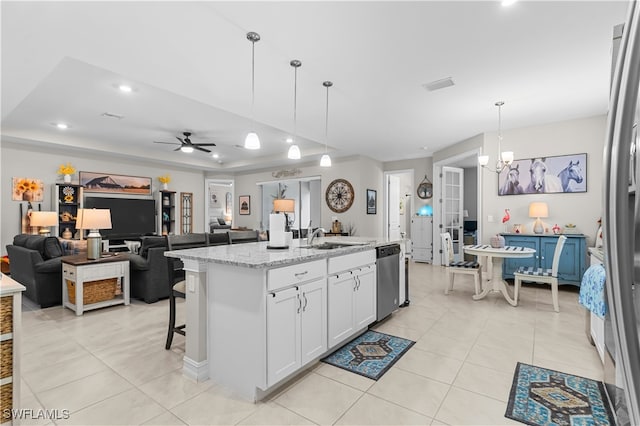 kitchen with hanging light fixtures, white cabinetry, a kitchen island with sink, dishwasher, and light stone counters