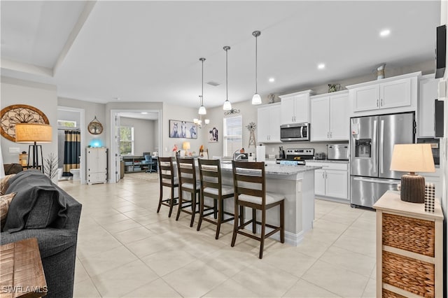 kitchen with stainless steel appliances, an island with sink, and white cabinets