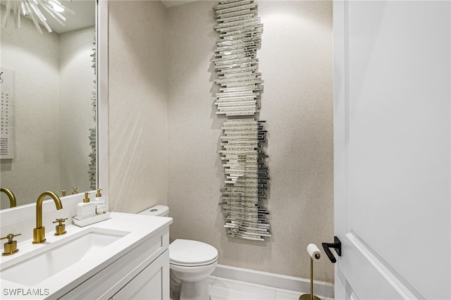 bathroom with tile patterned floors, vanity, a chandelier, and toilet