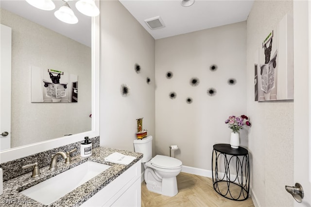 bathroom with parquet flooring, vanity, and toilet