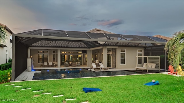 rear view of property featuring glass enclosure, a patio area, and a yard