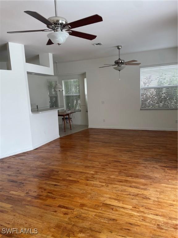 592 Crossfield Cir, Naples, FL 34104 - unfurnished living room with a ceiling fan, wood finished floors, and baseboards
