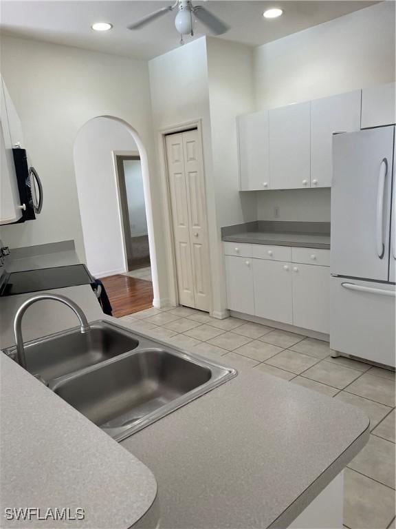 592 Crossfield Cir, Naples, FL 34104 - kitchen with freestanding refrigerator, arched walkways, white cabinets, a ceiling fan, and light tile patterned floors