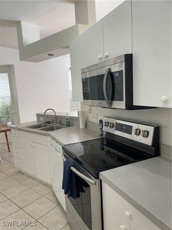 kitchen with white cabinets, appliances with stainless steel finishes, light tile patterned flooring, and sink