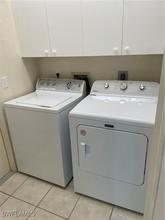 laundry area with cabinets, washing machine and dryer, and light tile patterned flooring