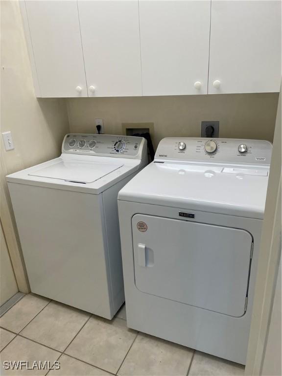 592 Crossfield Cir, Naples, FL 34104 - laundry room with washer and dryer, cabinet space, and light tile patterned floors