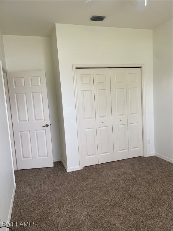 unfurnished bedroom featuring dark colored carpet and a closet