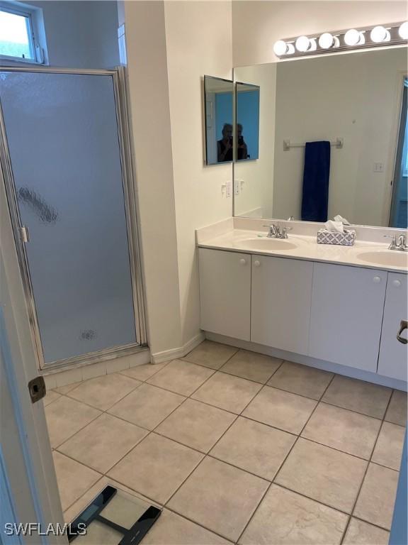 592 Crossfield Cir, Naples, FL 34104 - bathroom with tile patterned flooring, a stall shower, double vanity, and baseboards