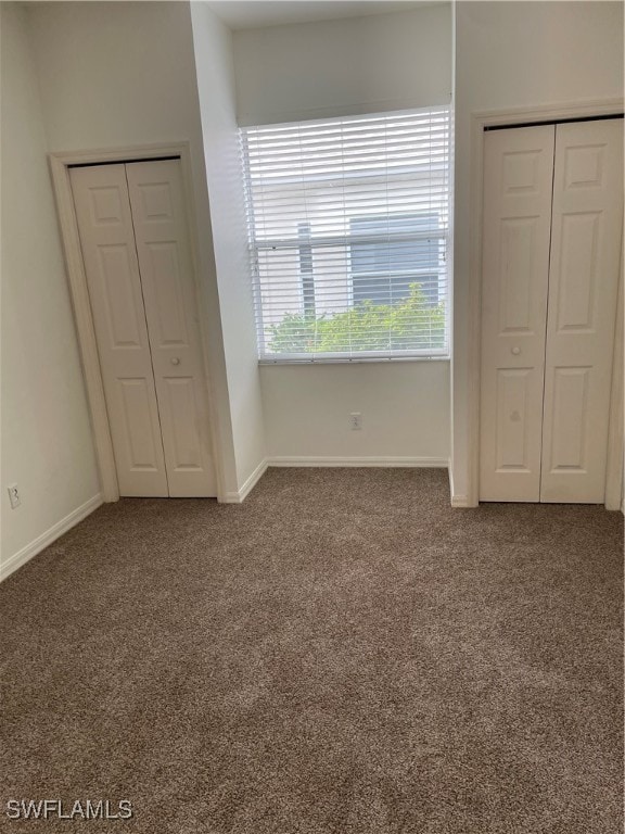 unfurnished bedroom featuring two closets and carpet