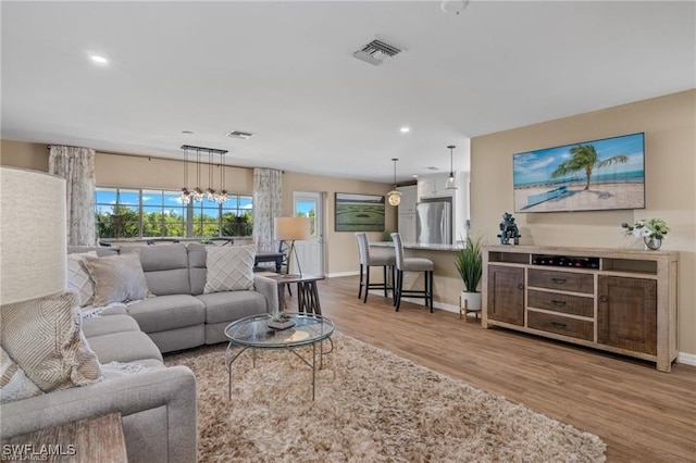 living room featuring a notable chandelier and light hardwood / wood-style floors