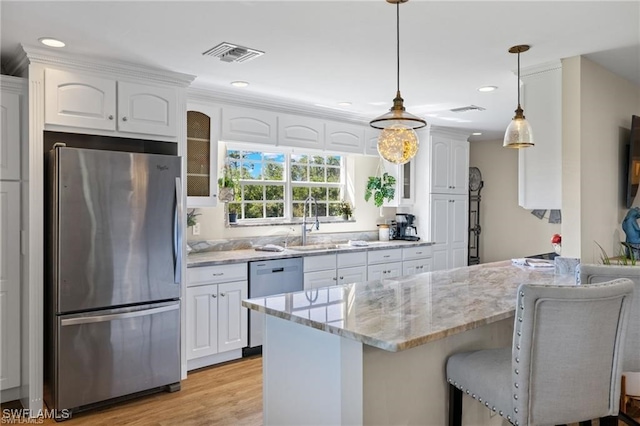 kitchen featuring a breakfast bar area, stainless steel appliances, light stone countertops, pendant lighting, and white cabinetry