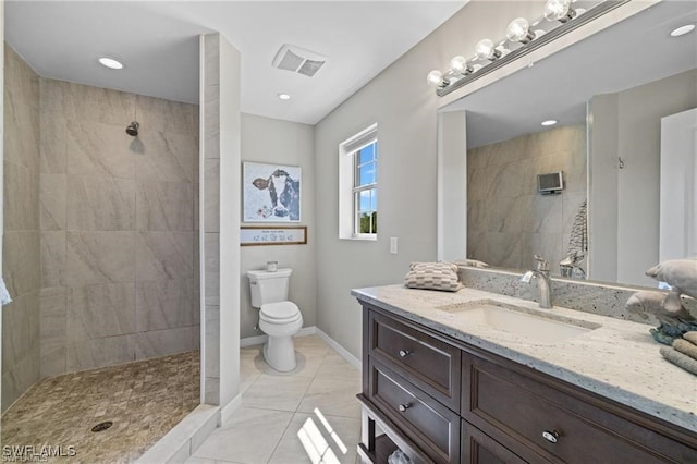 bathroom featuring vanity, a tile shower, toilet, and tile patterned flooring