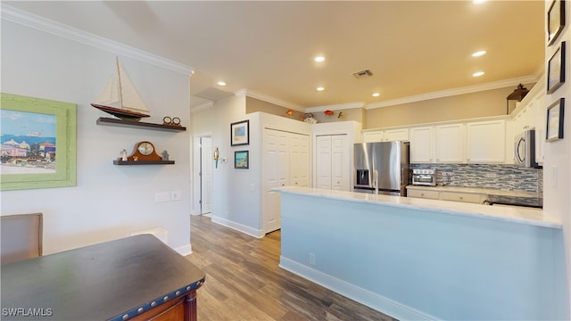 kitchen featuring white cabinetry, stainless steel appliances, hardwood / wood-style flooring, and crown molding