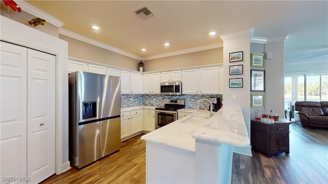 kitchen with stainless steel appliances, sink, hardwood / wood-style flooring, white cabinets, and kitchen peninsula