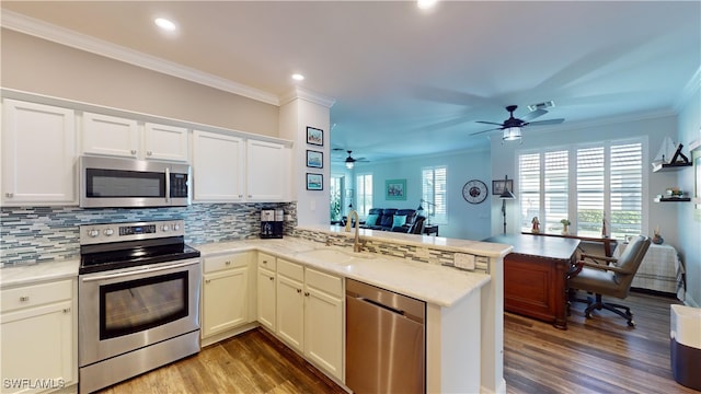 kitchen with stainless steel appliances, sink, dark wood-type flooring, and kitchen peninsula