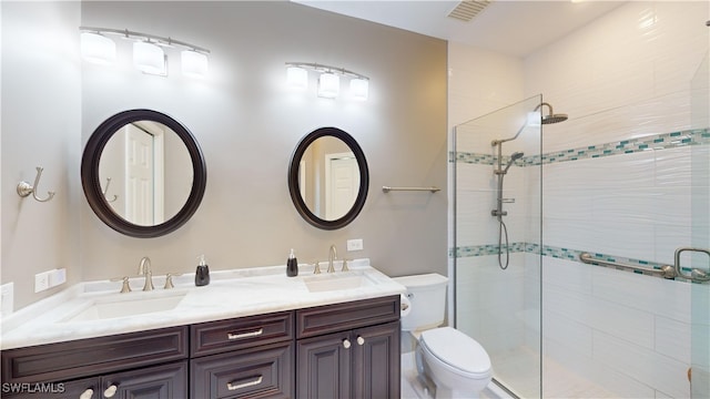 bathroom featuring toilet, vanity, and a shower with door