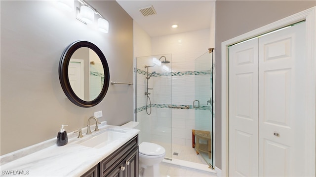 bathroom featuring a shower with door, vanity, toilet, and tile patterned floors