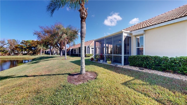 view of yard with a sunroom and a water view