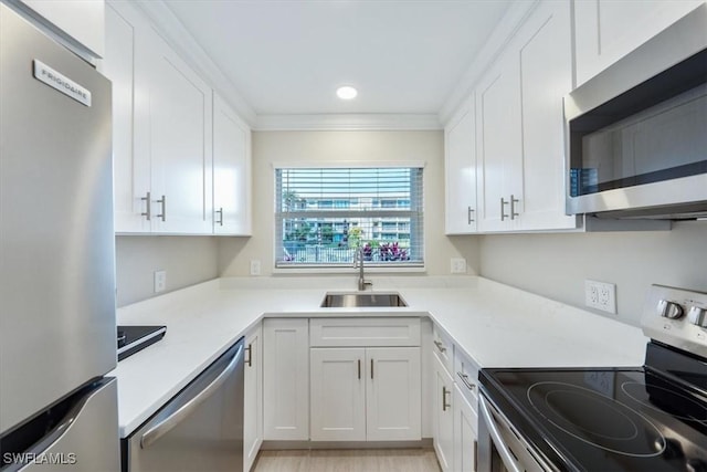 kitchen with sink, crown molding, stainless steel appliances, and white cabinets