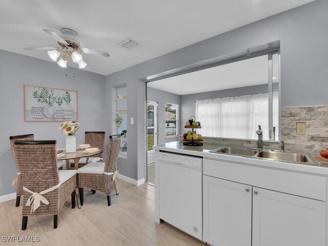 kitchen with sink, dishwasher, white cabinetry, and light hardwood / wood-style flooring