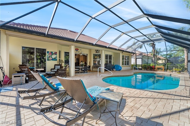 view of pool featuring glass enclosure, ceiling fan, and a patio area